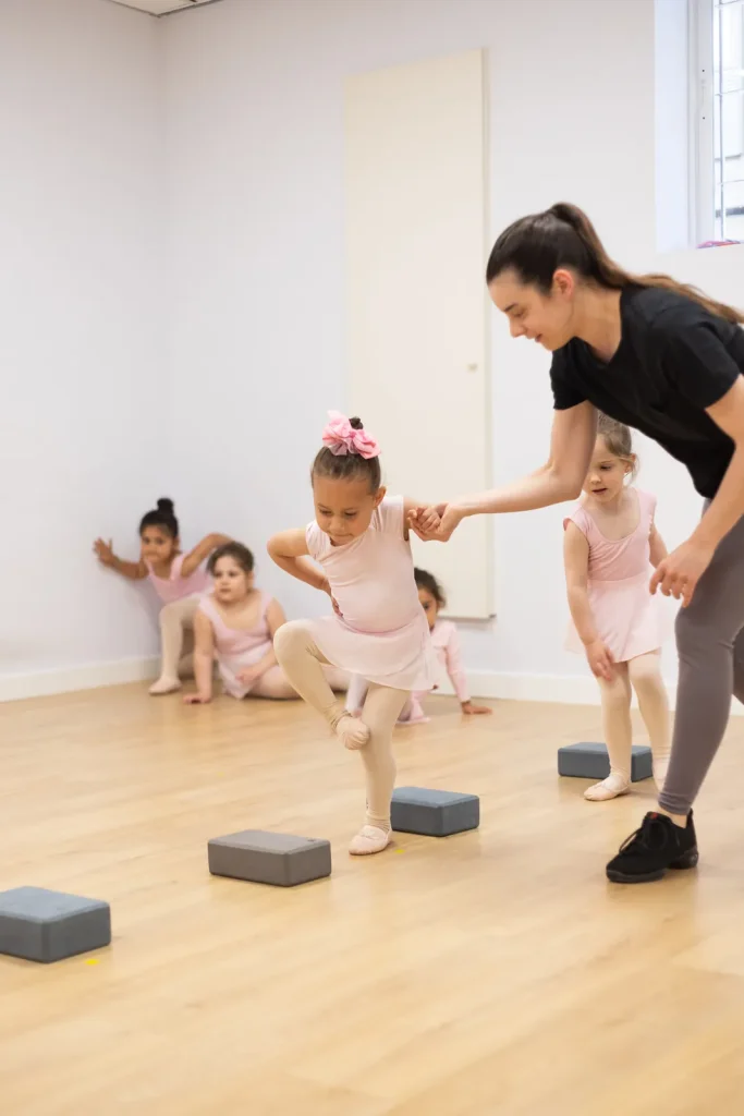 Profesora de CDAM ayudando de la mano a una alumna de pre ballet