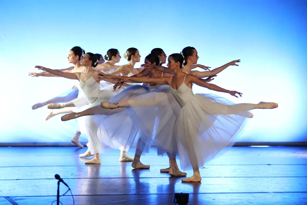 Cuerpo de baile de CDAM en arabesque con luz azul en el festival de fin de curso