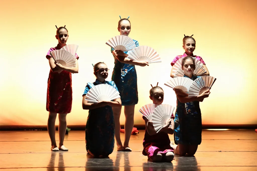 Coreografía con abanicos y luz cálida en el festival de CDAM