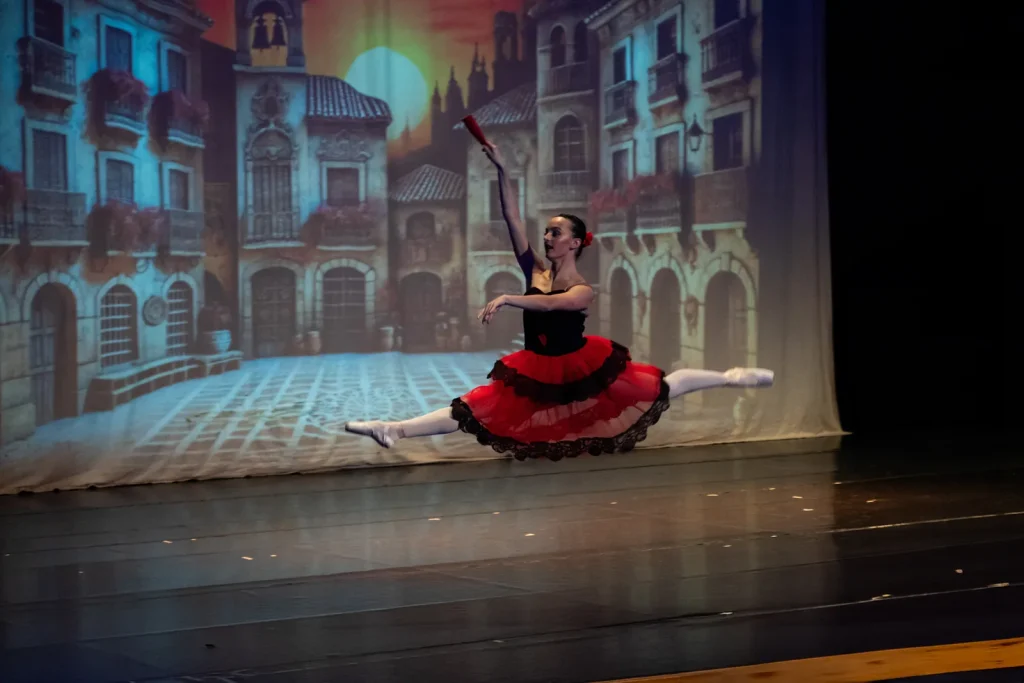Grand jeté con tutú rojo y luz teatral en la Gala Española de CDAM
