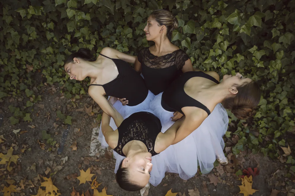 Imagen cenital de cuatro bailarinas de CDAM tumbadas sobre hiedra y hojas de otoño